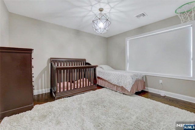 bedroom with baseboards, visible vents, and wood finished floors