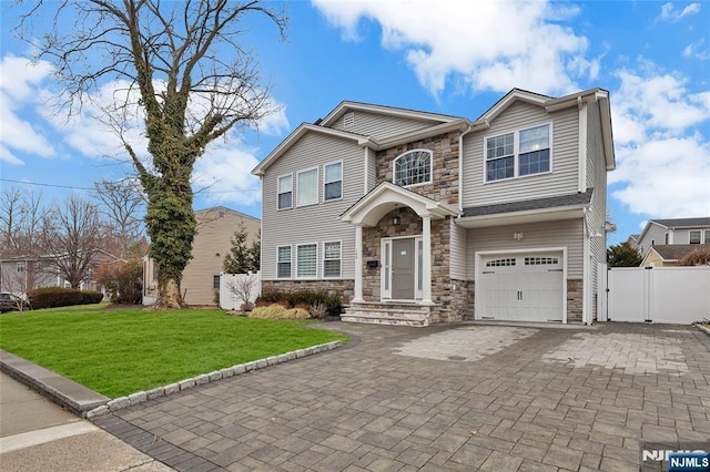 view of front of home featuring stone siding, a front lawn, fence, and a gate