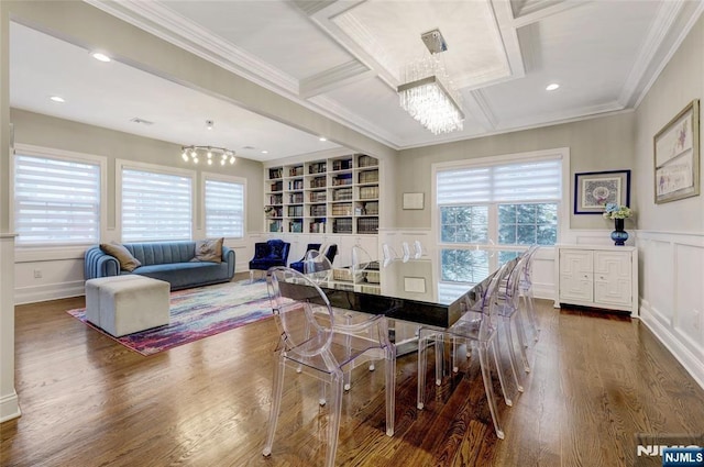 dining space with built in shelves, a decorative wall, wood finished floors, ornamental molding, and an inviting chandelier