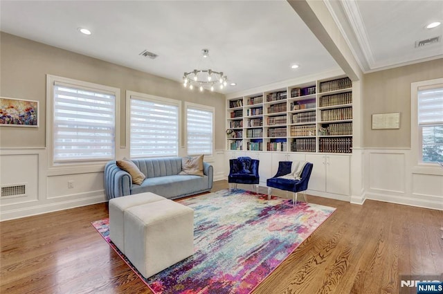 living area featuring built in features, visible vents, and a decorative wall