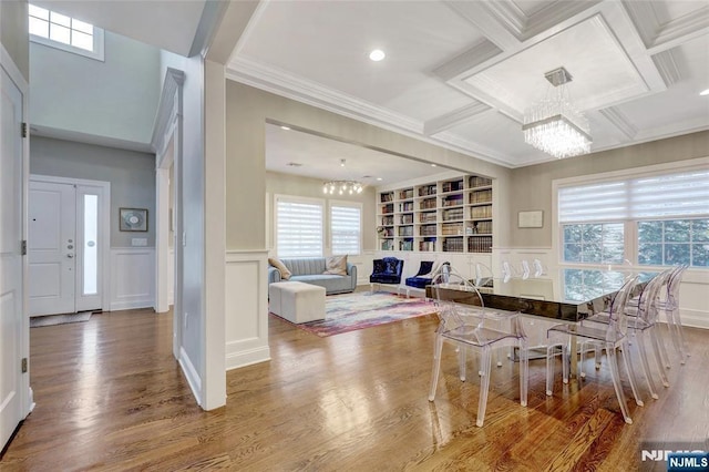 dining room featuring a chandelier, coffered ceiling, beamed ceiling, and a decorative wall