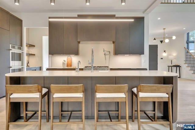 kitchen with a breakfast bar, light countertops, a large island, and modern cabinets