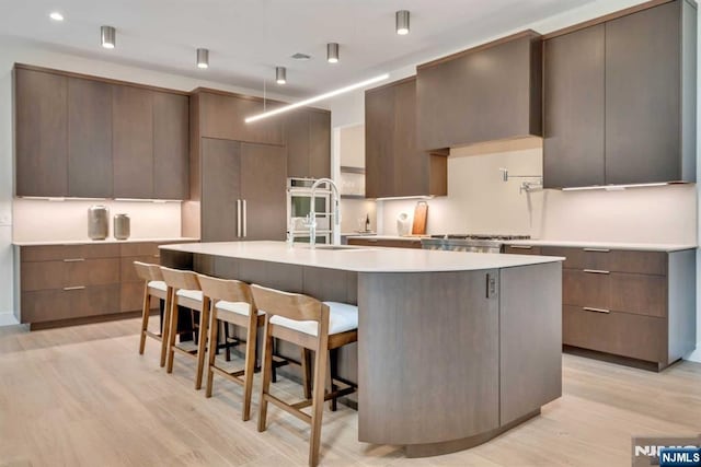 kitchen featuring light countertops, modern cabinets, and a kitchen island with sink