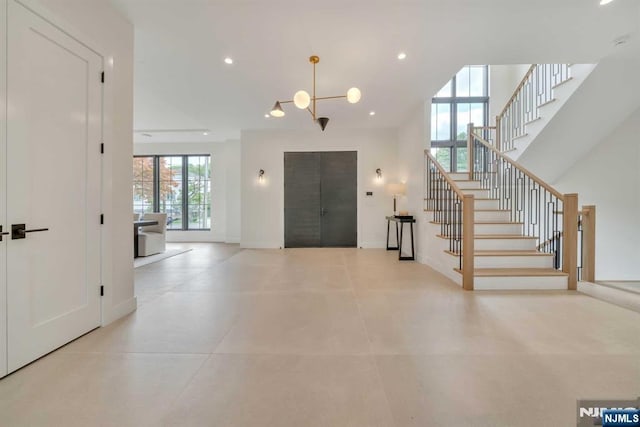 foyer entrance with baseboards, stairs, a high ceiling, a notable chandelier, and recessed lighting