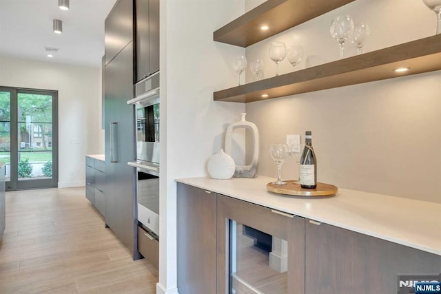 kitchen featuring light countertops, open shelves, light wood finished floors, and modern cabinets