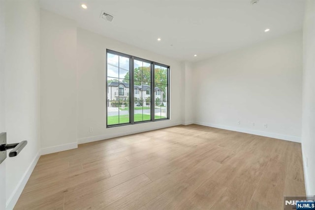 unfurnished room with baseboards, light wood finished floors, and recessed lighting