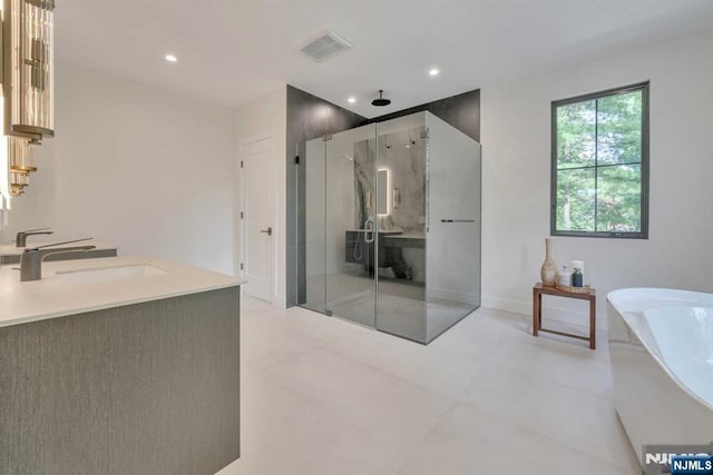 bathroom with a marble finish shower, recessed lighting, a soaking tub, visible vents, and vanity