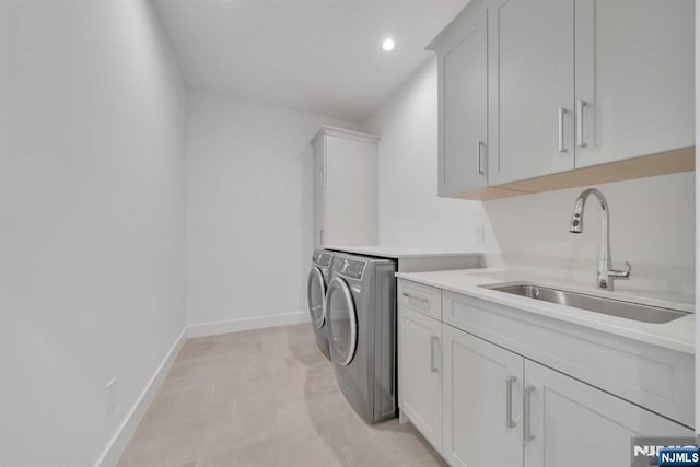 washroom with cabinet space, baseboards, independent washer and dryer, a sink, and recessed lighting