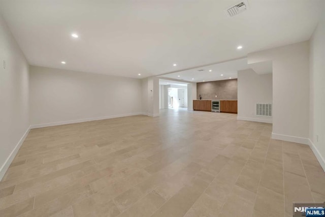 unfurnished living room featuring baseboards, wine cooler, visible vents, and recessed lighting