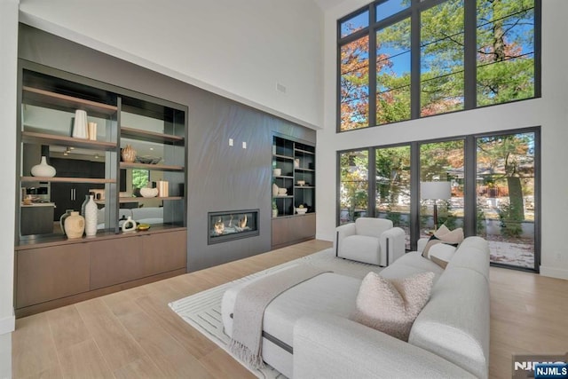 living area featuring visible vents, wood finished floors, a high ceiling, built in shelves, and a fireplace