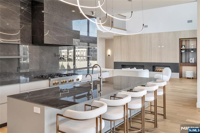 kitchen featuring light wood-style floors, modern cabinets, a kitchen breakfast bar, and a glass covered fireplace