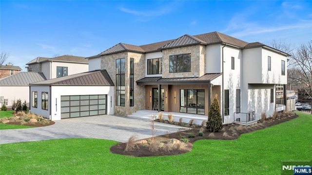 view of front facade featuring a garage, stone siding, decorative driveway, a front lawn, and a standing seam roof