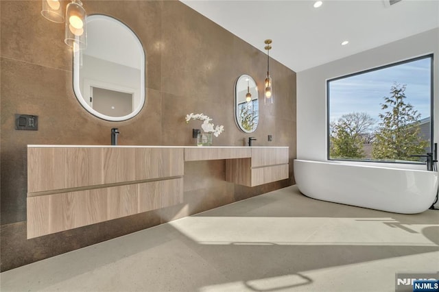 full bathroom with double vanity, vaulted ceiling, a freestanding bath, tile walls, and recessed lighting