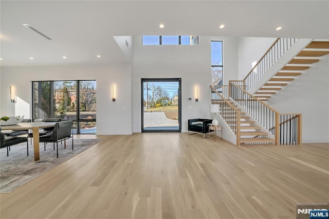 entrance foyer featuring light wood-style floors, recessed lighting, stairway, and a towering ceiling