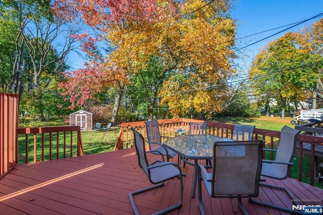 deck featuring a storage shed, outdoor dining area, an outdoor structure, and a lawn