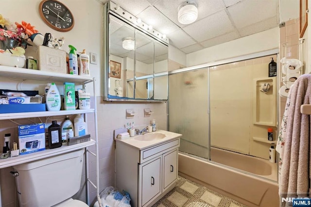 full bathroom with a paneled ceiling, combined bath / shower with glass door, vanity, and toilet