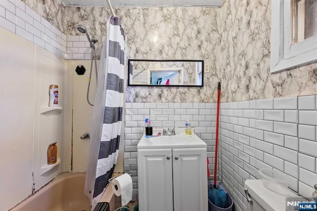 full bathroom with wallpapered walls, a wainscoted wall, shower / bath combo with shower curtain, vanity, and tile walls