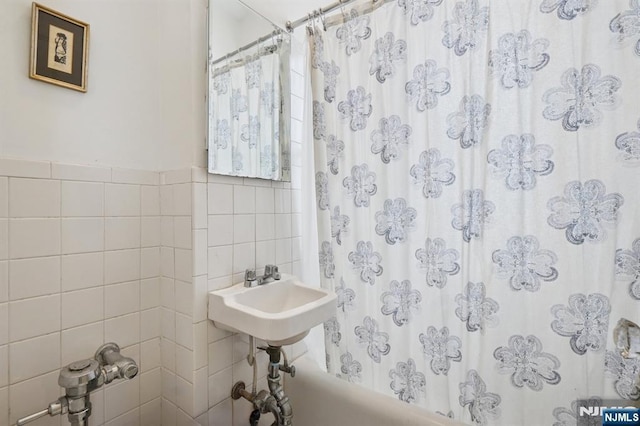 full bath featuring a sink, tile walls, and shower / tub combo with curtain