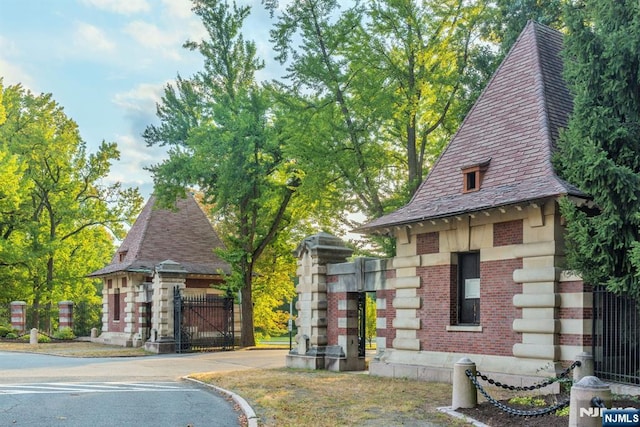 view of front of house featuring brick siding, a high end roof, and a gate