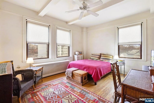 bedroom with a ceiling fan, radiator, beam ceiling, and wood finished floors