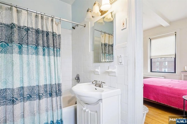 bathroom featuring wood finished floors, tile walls, tasteful backsplash, beamed ceiling, and shower / bath combination with curtain