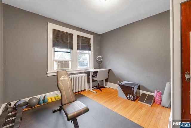 exercise room with baseboards, radiator heating unit, cooling unit, and wood finished floors