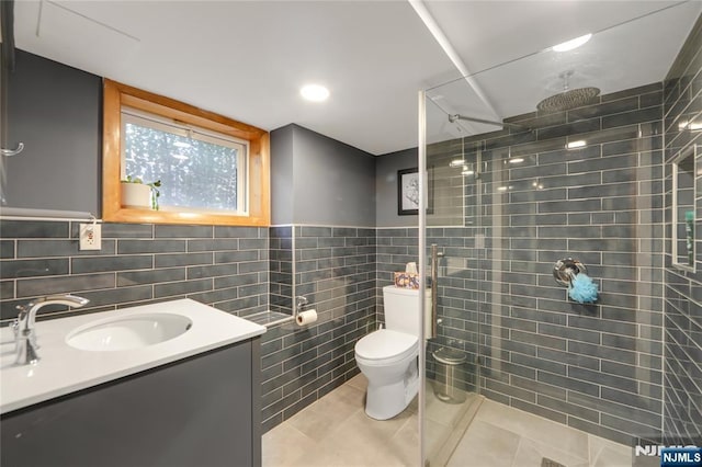 full bath with toilet, tile patterned flooring, a tile shower, vanity, and tile walls