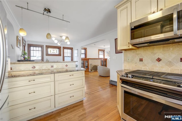 kitchen with decorative backsplash, ornamental molding, stainless steel appliances, cream cabinetry, and light wood-style floors