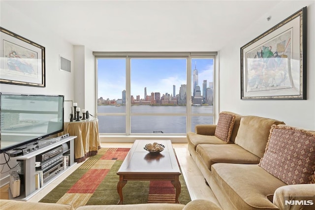 living room with visible vents, a wall of windows, and a city view