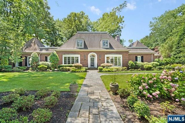 view of front of property with a front lawn, a chimney, and brick siding