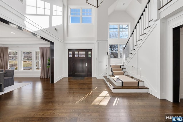 foyer with visible vents, a high ceiling, wood finished floors, baseboards, and stairs