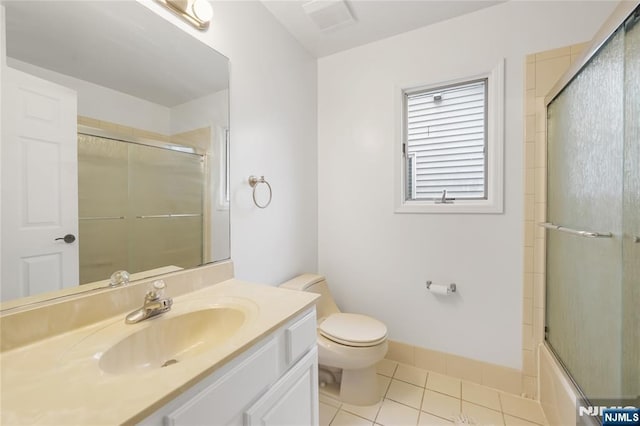 bathroom featuring toilet, enclosed tub / shower combo, vanity, baseboards, and tile patterned floors