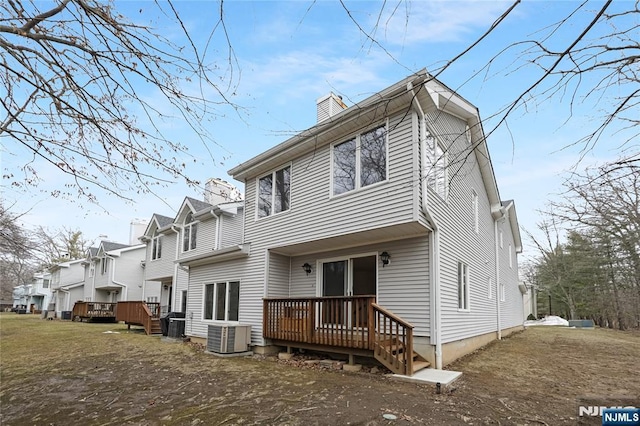 back of property with a chimney, a deck, and cooling unit