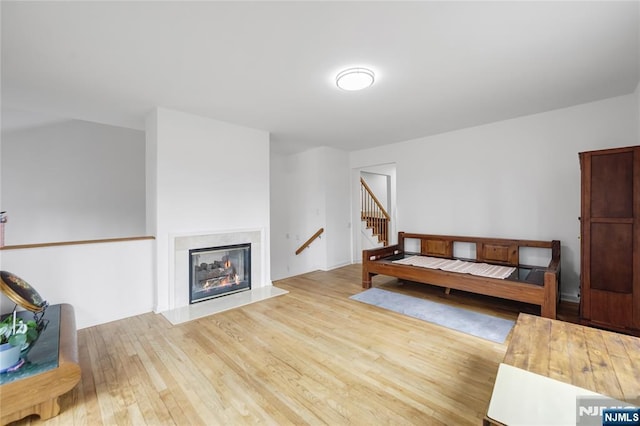 living room featuring stairway, light wood finished floors, and a premium fireplace