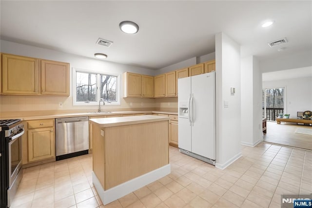 kitchen featuring appliances with stainless steel finishes, light countertops, a sink, and visible vents