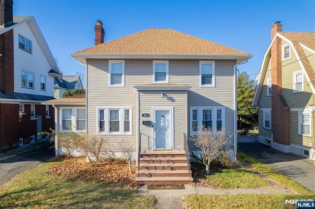 view of front of property with a shingled roof and a chimney