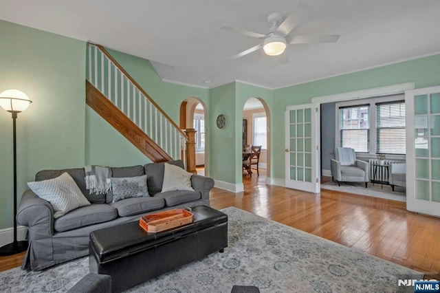living area featuring arched walkways, a wealth of natural light, french doors, and wood finished floors