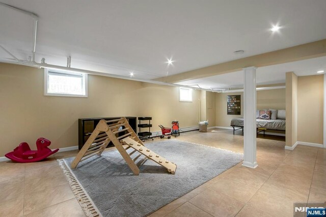 recreation room featuring baseboards, a baseboard radiator, and light tile patterned flooring