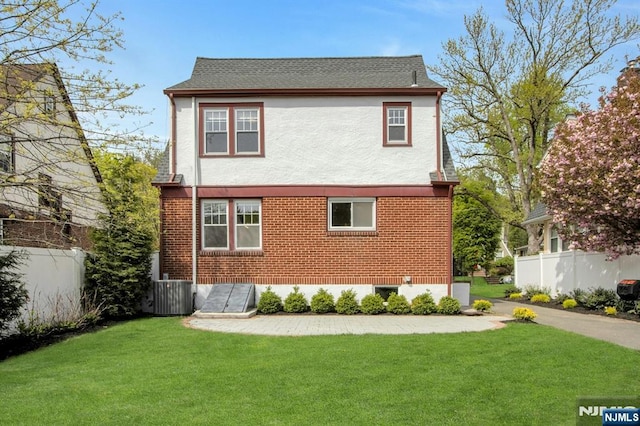 exterior space with a lawn, brick siding, and fence