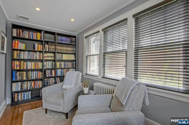 living area featuring crown molding, baseboards, visible vents, and radiator
