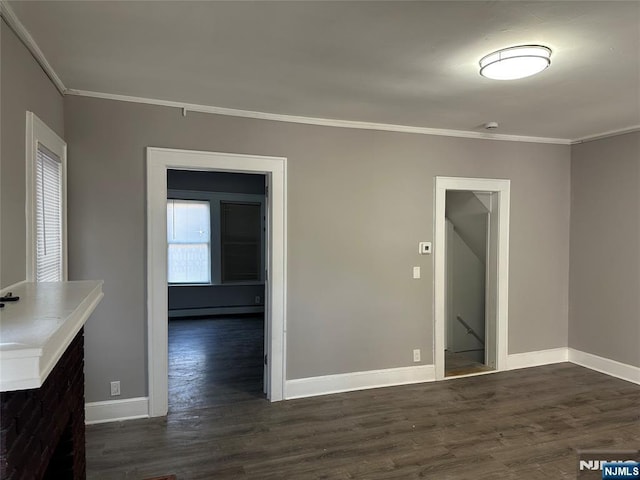 interior space featuring a baseboard heating unit, ornamental molding, dark wood-type flooring, and baseboards