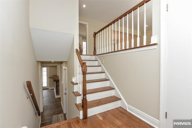 staircase featuring a wealth of natural light, recessed lighting, baseboards, and wood finished floors