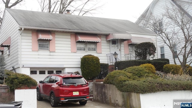 view of front facade featuring a garage, concrete driveway, and roof with shingles