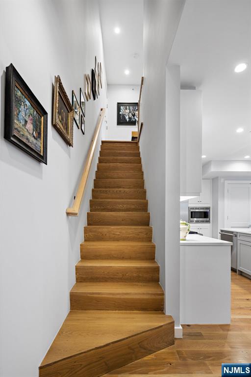 stairs with wood finished floors and recessed lighting