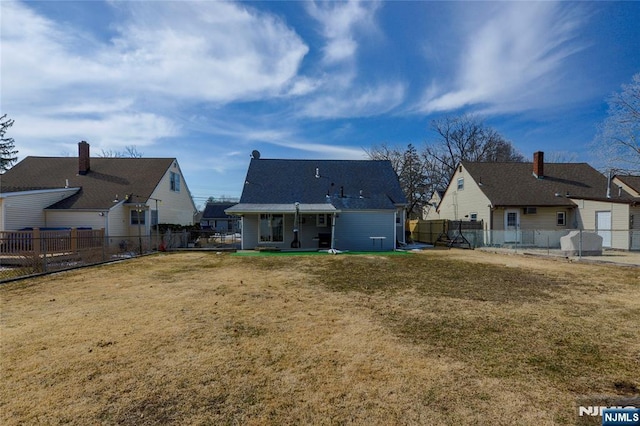 back of house featuring a fenced backyard, a residential view, and a yard