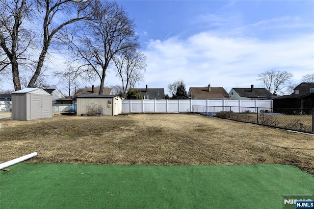 view of yard featuring an outbuilding, a storage unit, and a fenced backyard