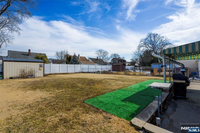 view of yard featuring an outbuilding, a fenced backyard, and a storage shed