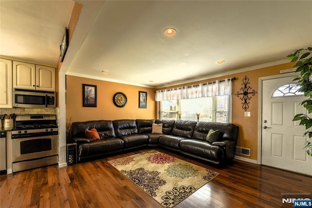 living area with dark wood-type flooring, visible vents, crown molding, and baseboards