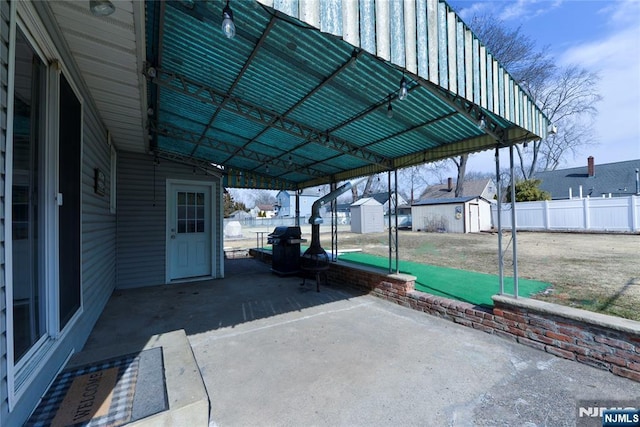 view of patio with a shed, fence, a carport, and an outdoor structure