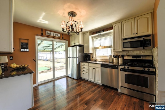 kitchen featuring dark wood finished floors, decorative light fixtures, an inviting chandelier, stainless steel appliances, and a sink